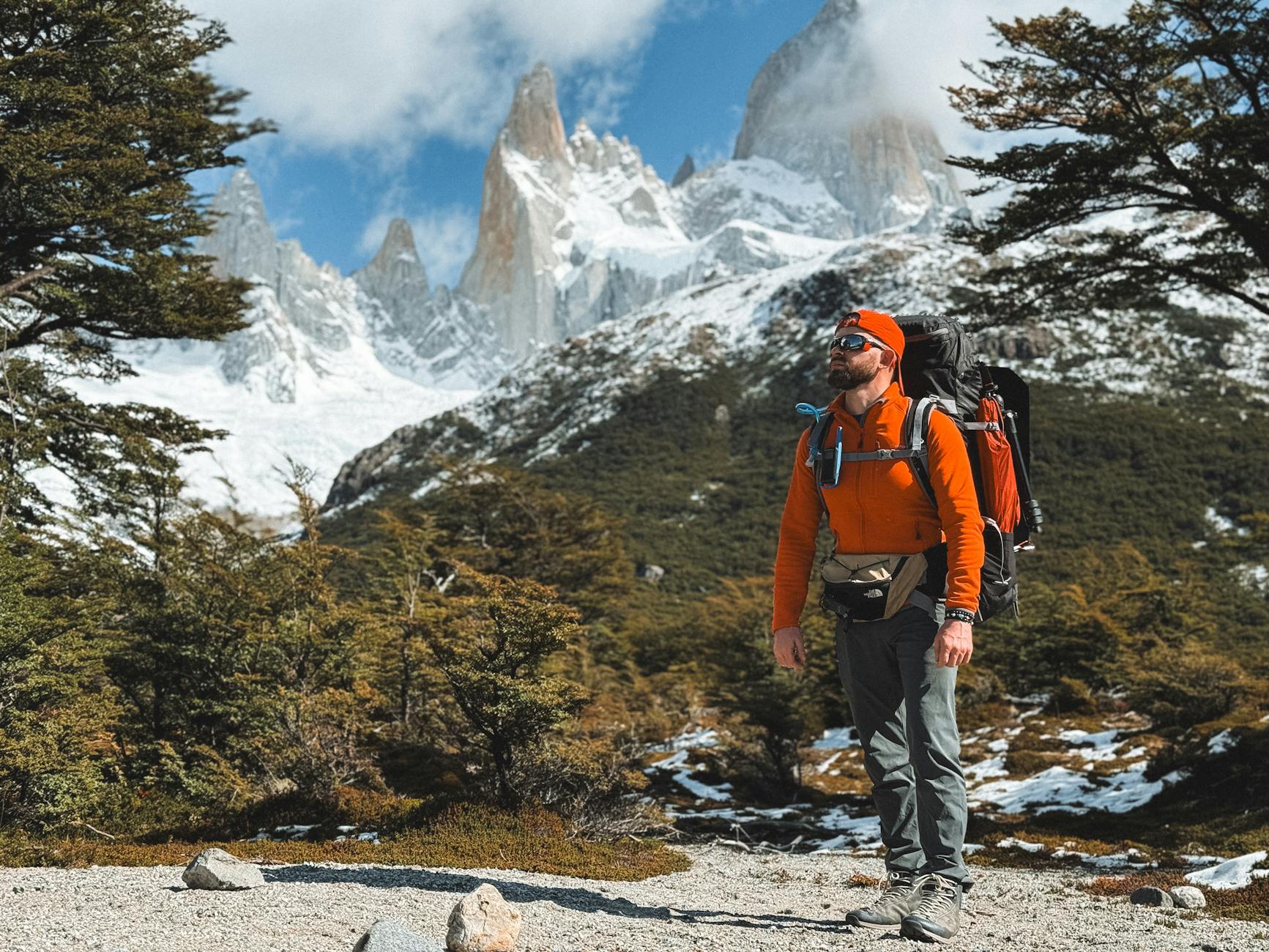 Misty Patagonian trail winding through golden plains toward jagged snow-capped peaks