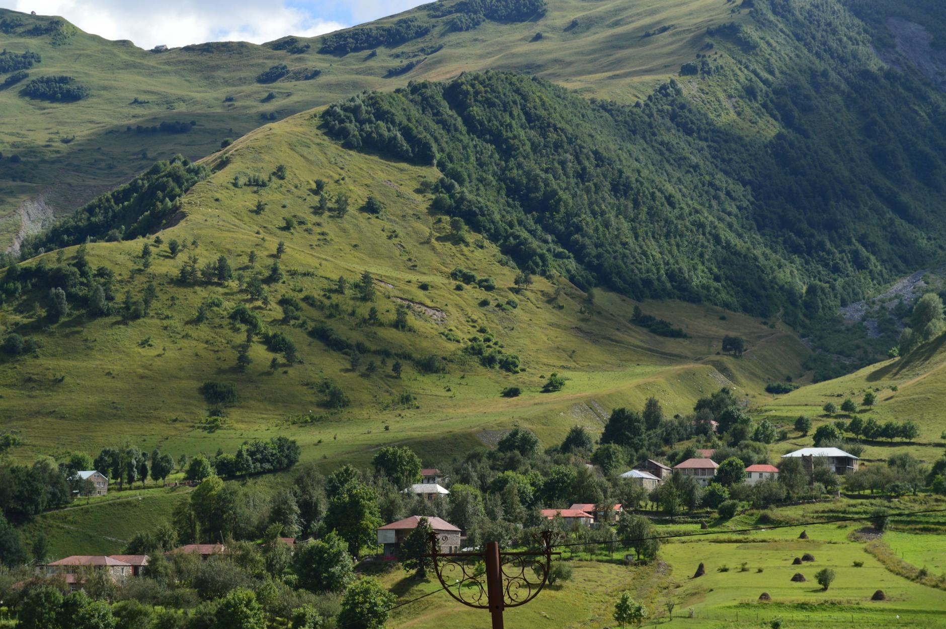Sunlit ancient stone tower rising over lush Caucasus mountain valley, Georgia
