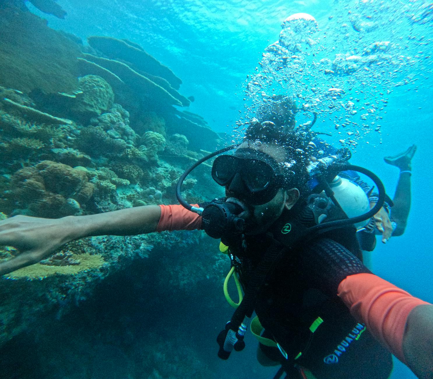 Snorkeler descending into crystal-clear Maldives waters above a vibrant coral reef