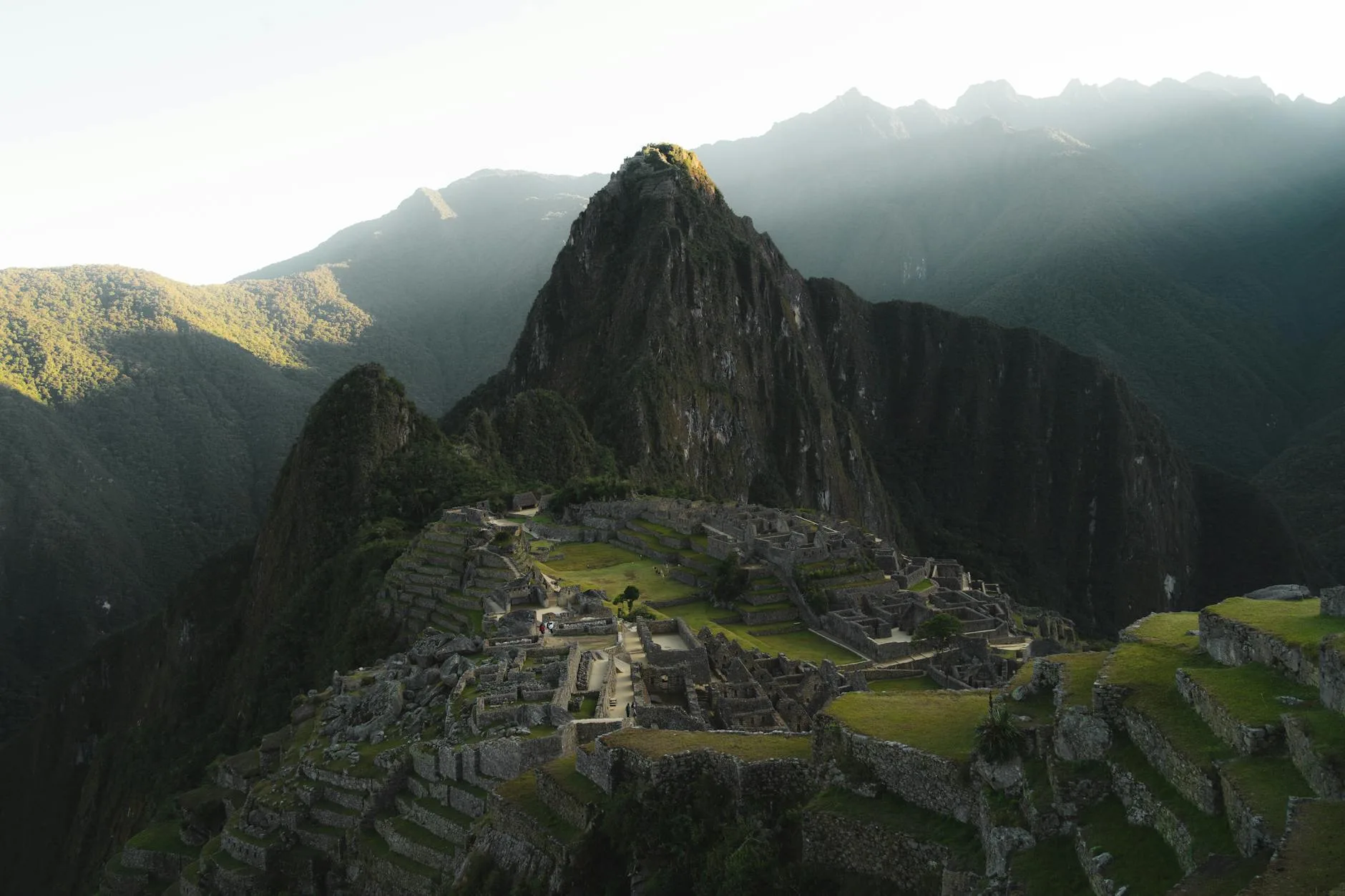 Hiker on misty Inca Trail stone path with ancient ruins and Andean peaks beyond