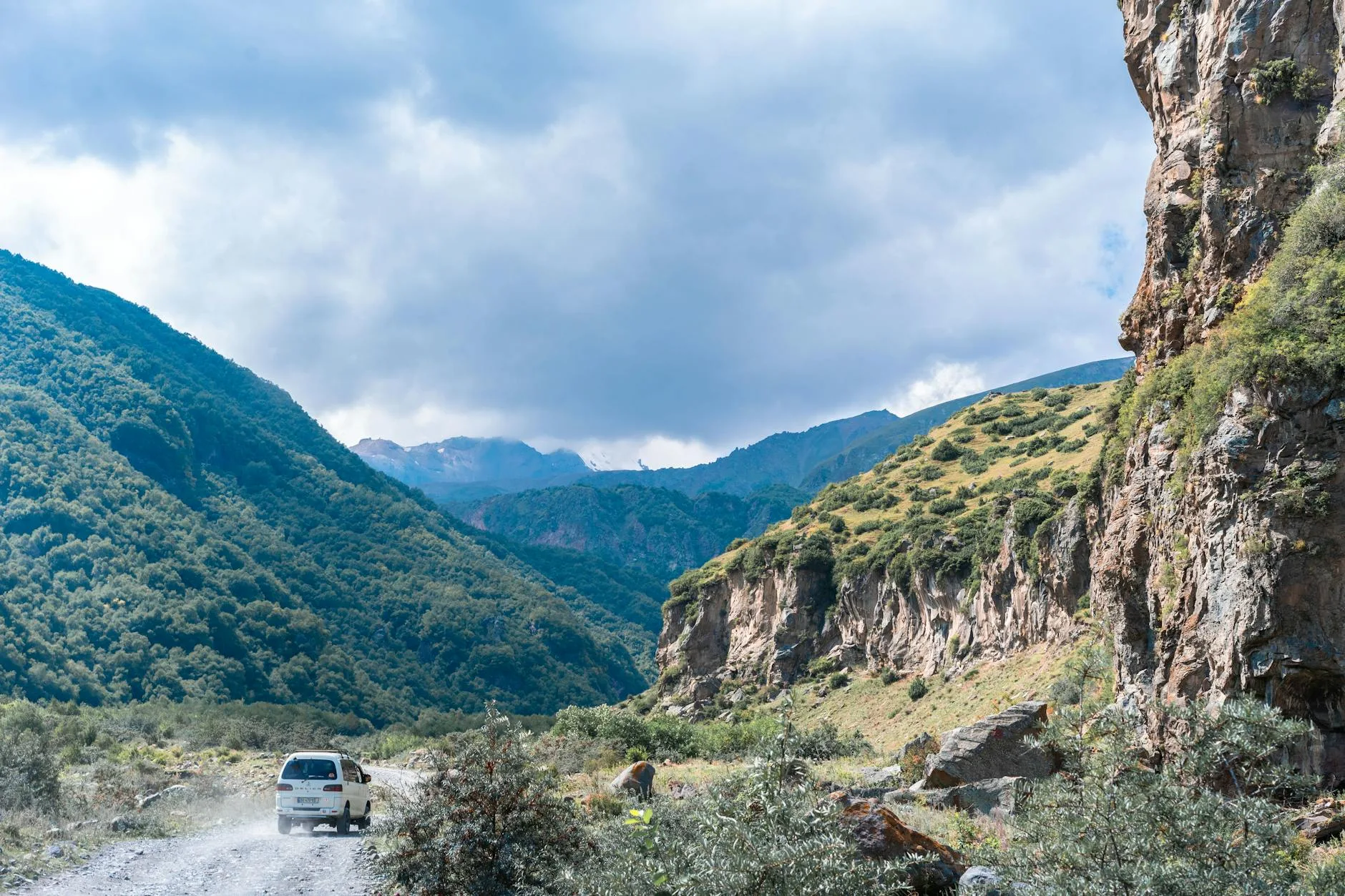 Winding mountain road through dramatic Caucasus peaks at golden hour