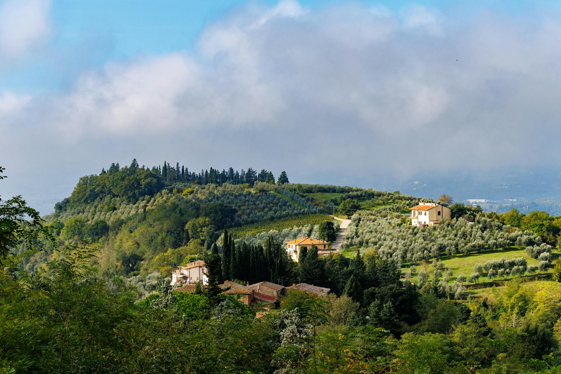 Sunlit Tuscan hillside village with terracotta rooftops and cypress trees at golden hour