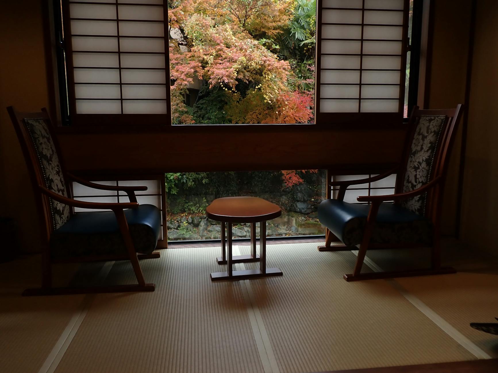 Wooden ryokan room with futon, shoji screens, and a view of a tranquil garden