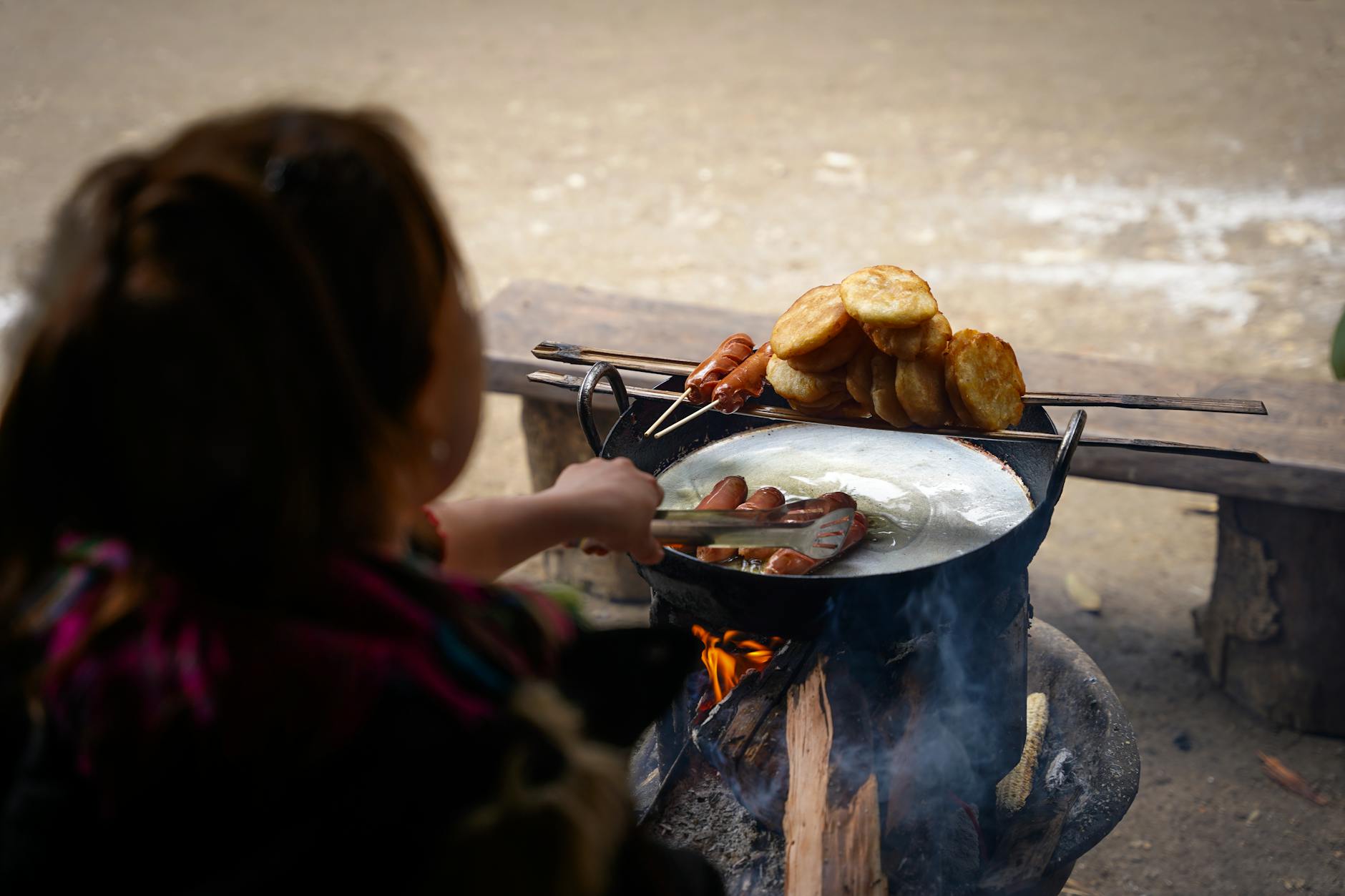 Hands shaping fresh rice paper dumplings over a wood-fired stove in rural Vietnam