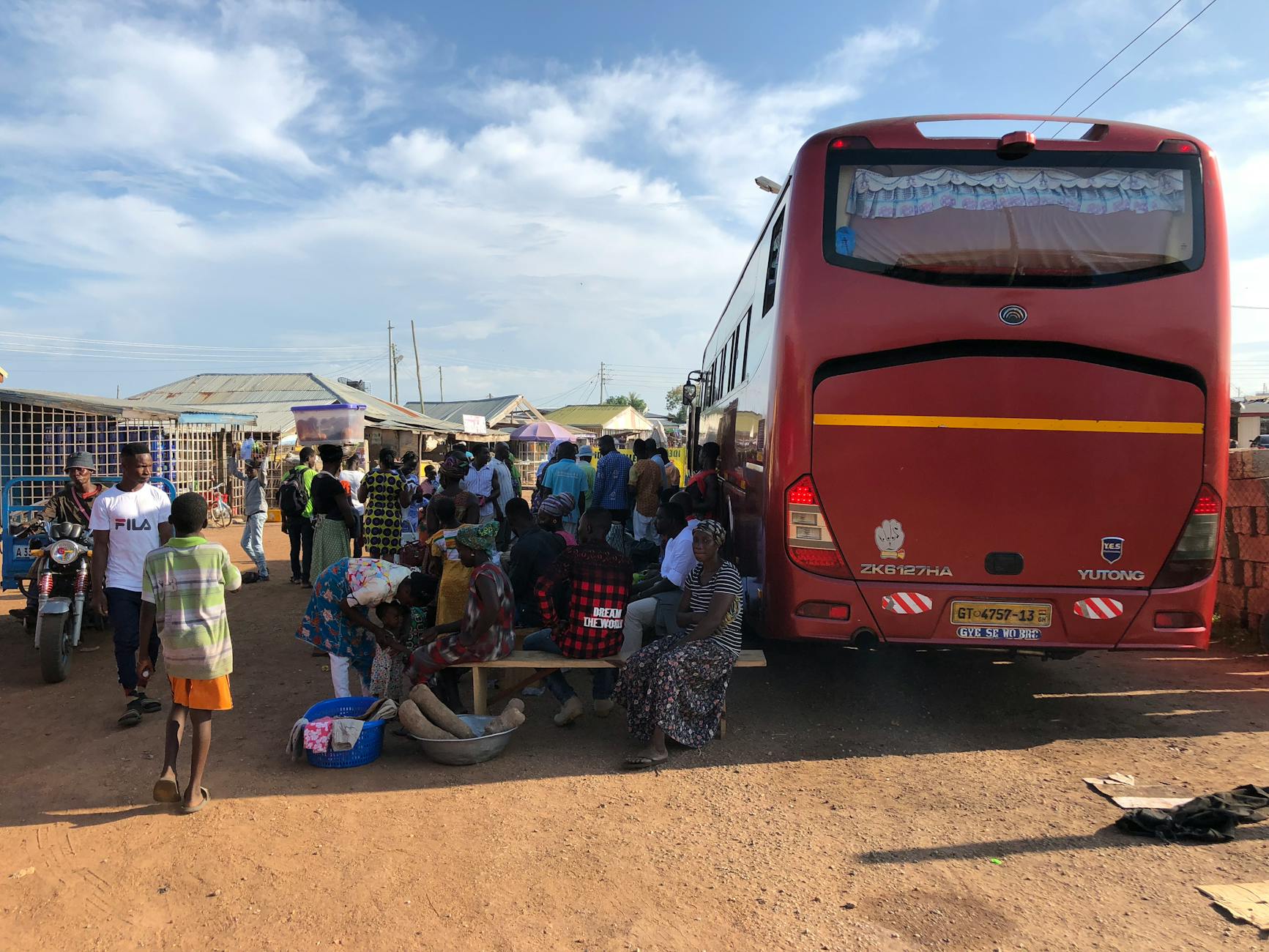 Colorful buses lined up at a dusty West African roadside market