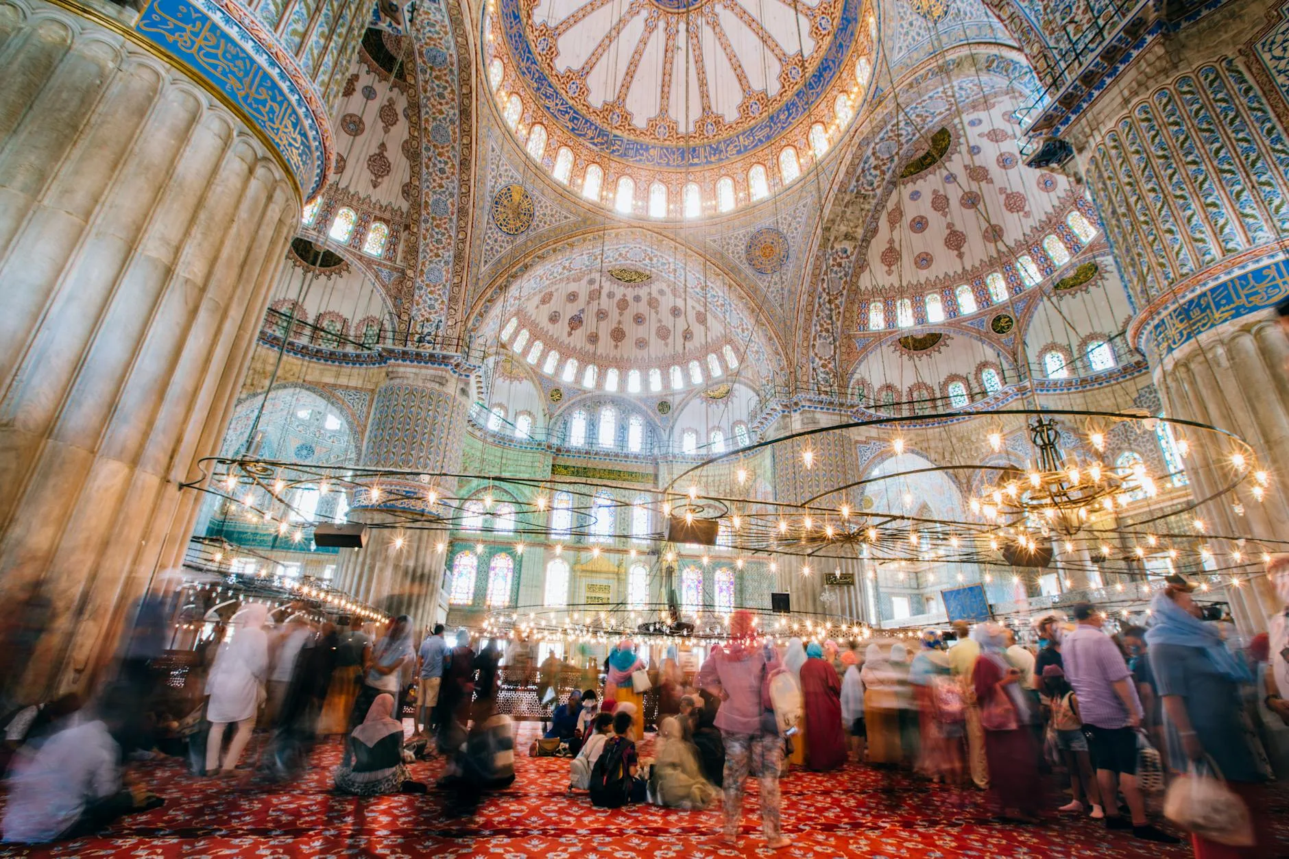 Tourists removing shoes before entering an ornate mosque with intricate tile work