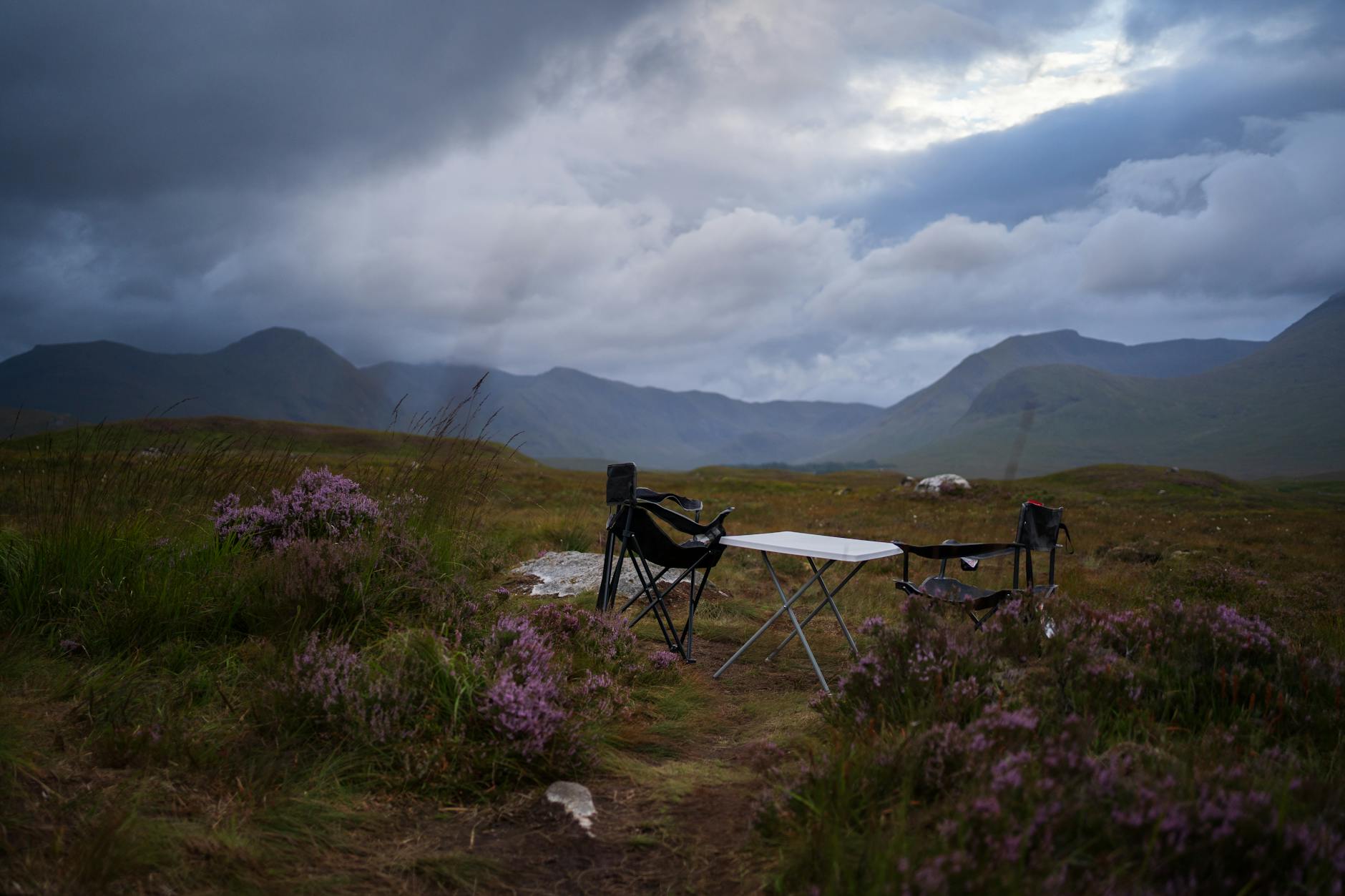 Misty Scottish highlands with a lone tent pitched beside a glassy loch at dawn