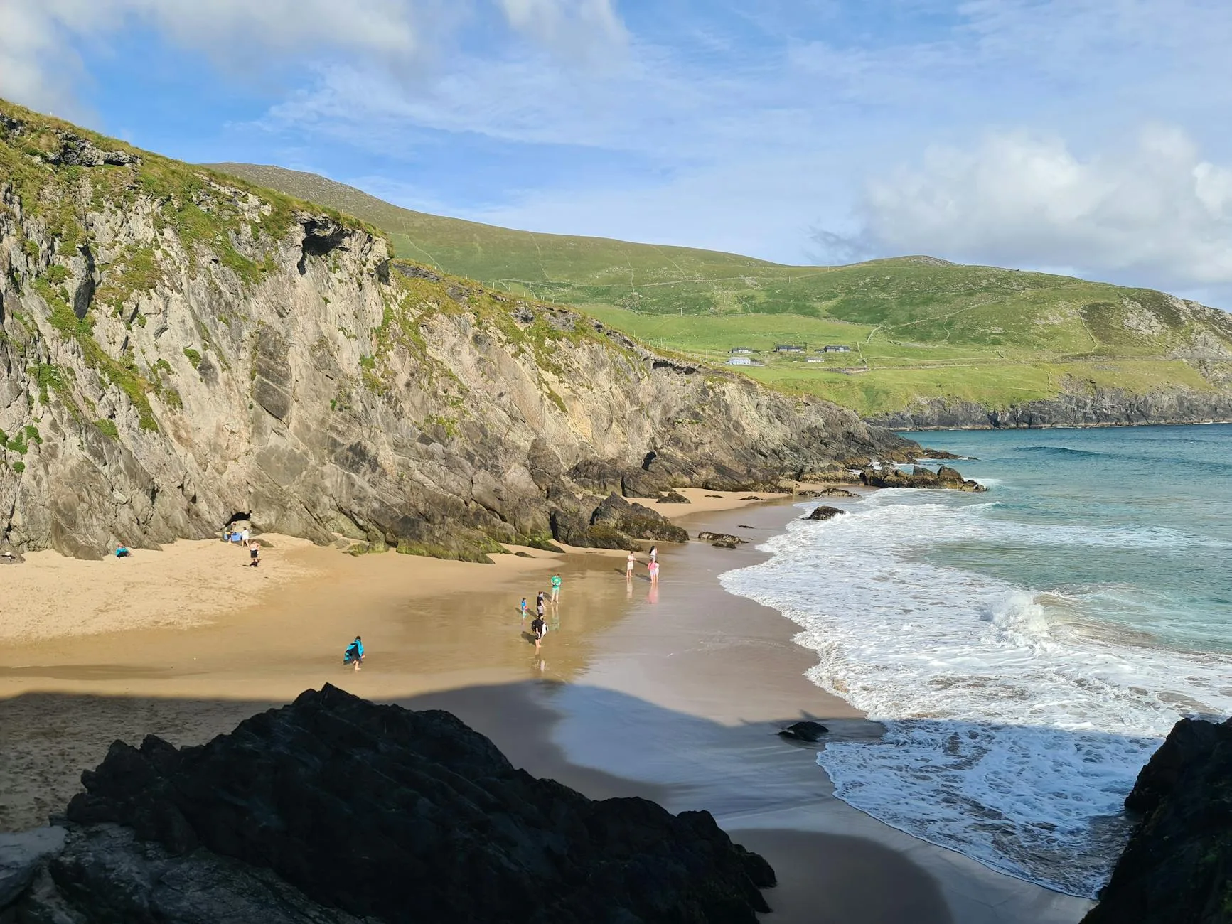 Swimmer diving into rugged Irish coastal waters beneath dramatic grey skies