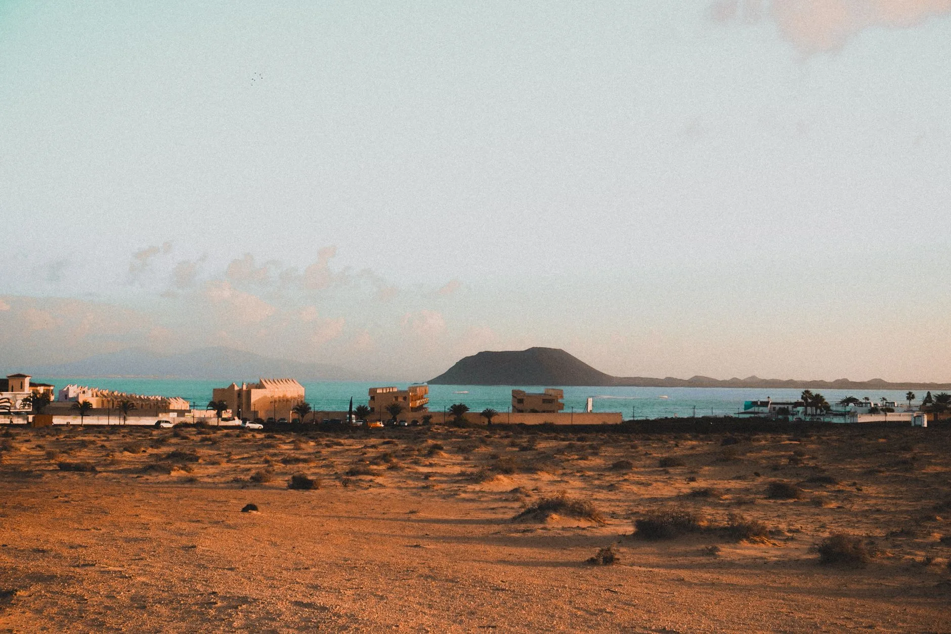 Colorful fishing boats on a volcanic black sand beach, Cape Verde island village beyond