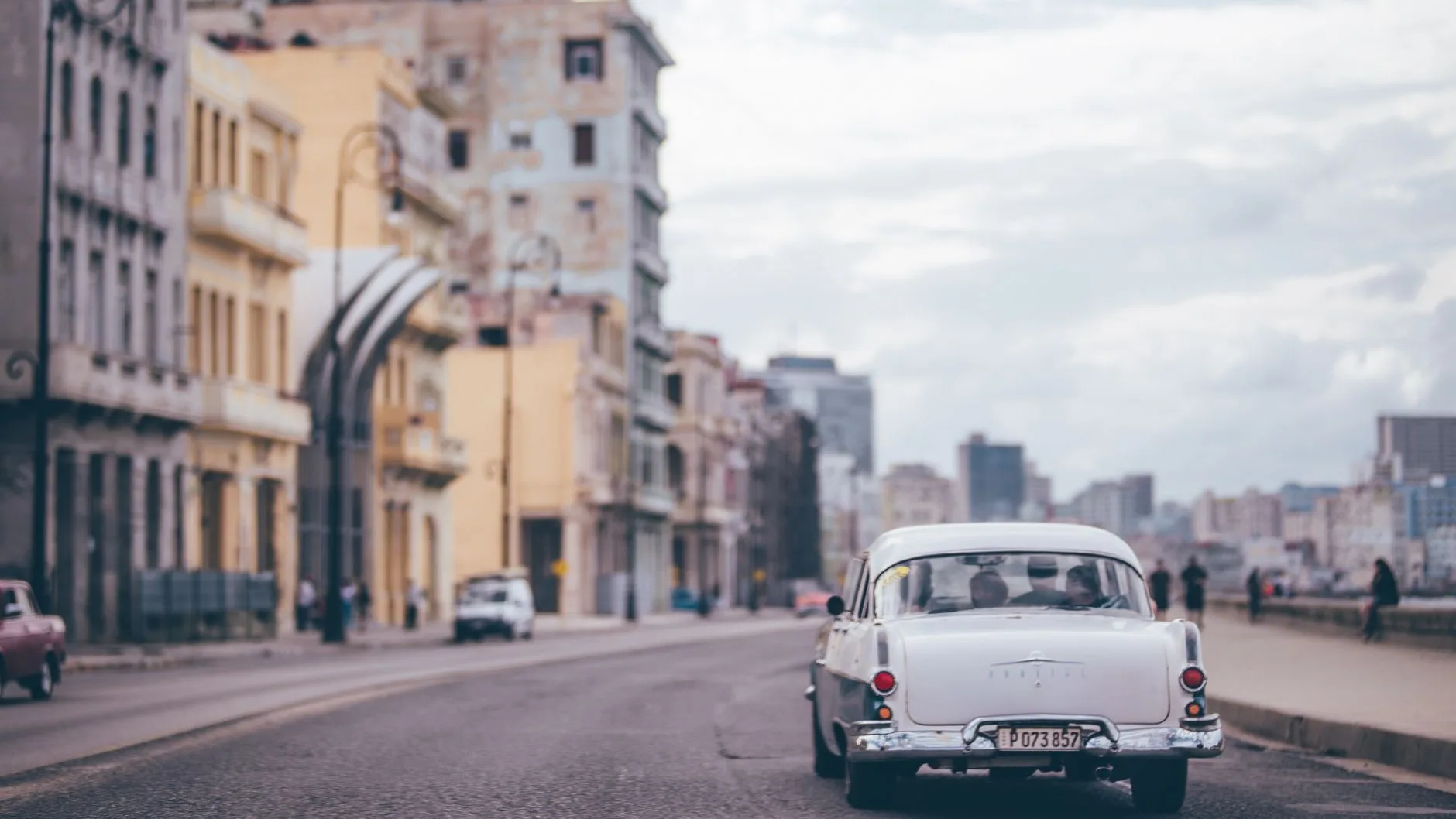 Colorful vintage cars lining a sun-drenched Havana street with pastel colonial buildings
