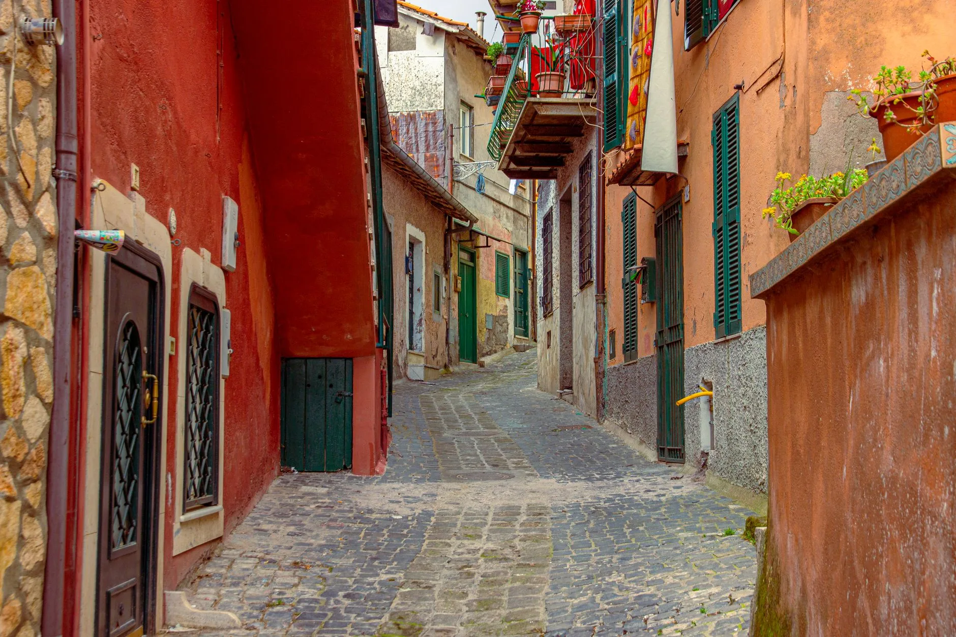 Sunlit cobblestone alley in a quiet Italian village, laundry strung between ancient stone walls