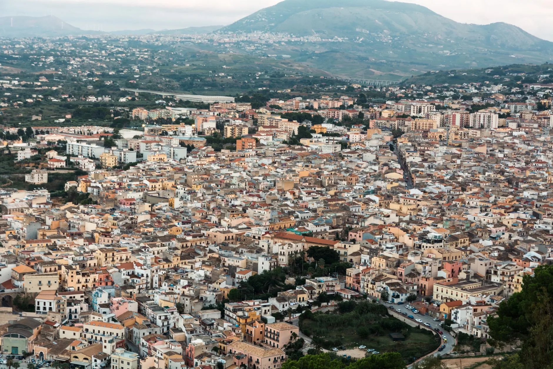 Sunlit Sicilian hillside village with terracotta rooftops overlooking the azure Mediterranean Sea