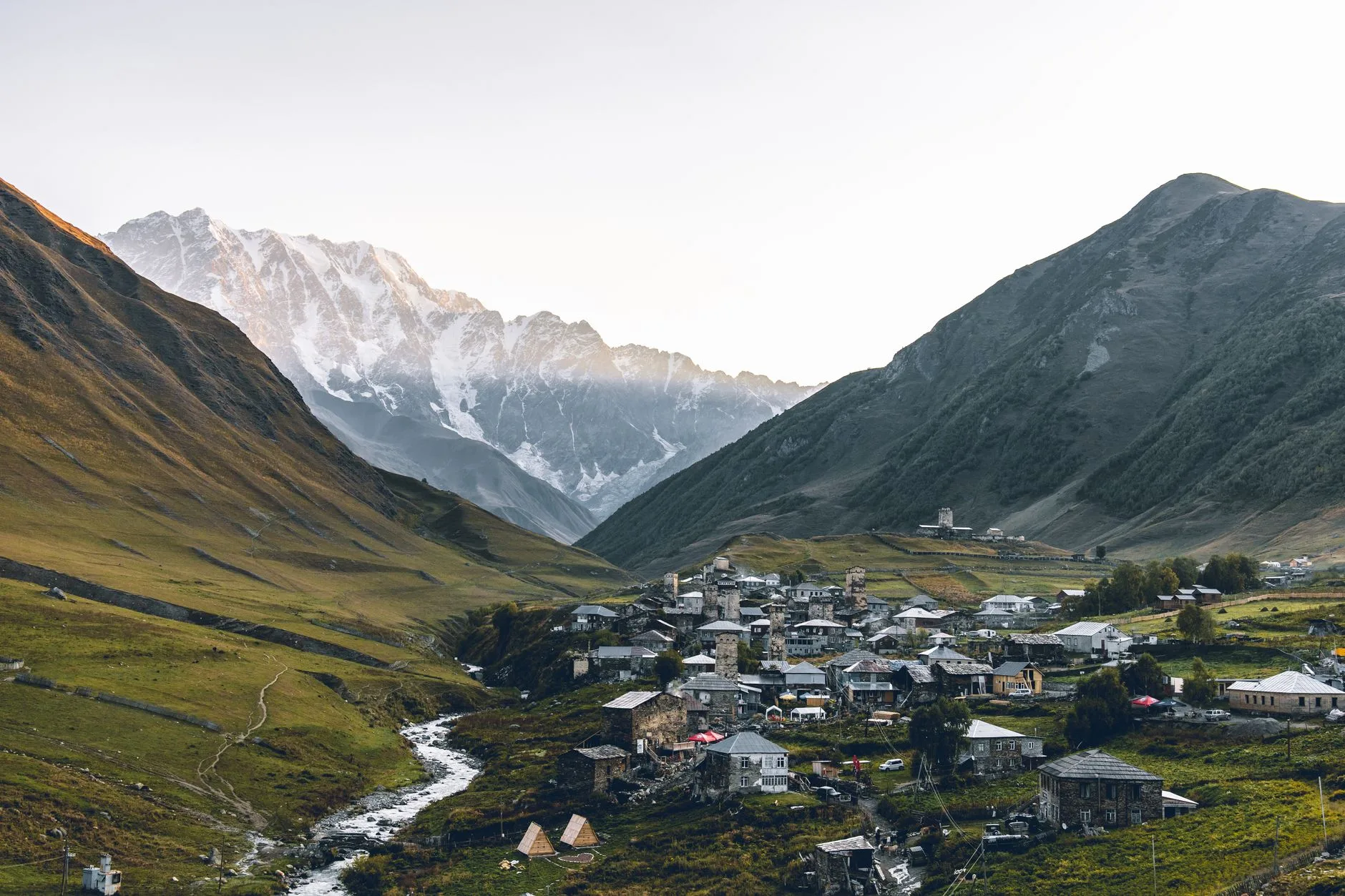 Misty Caucasus mountains rising above ancient Georgian villages at golden hour