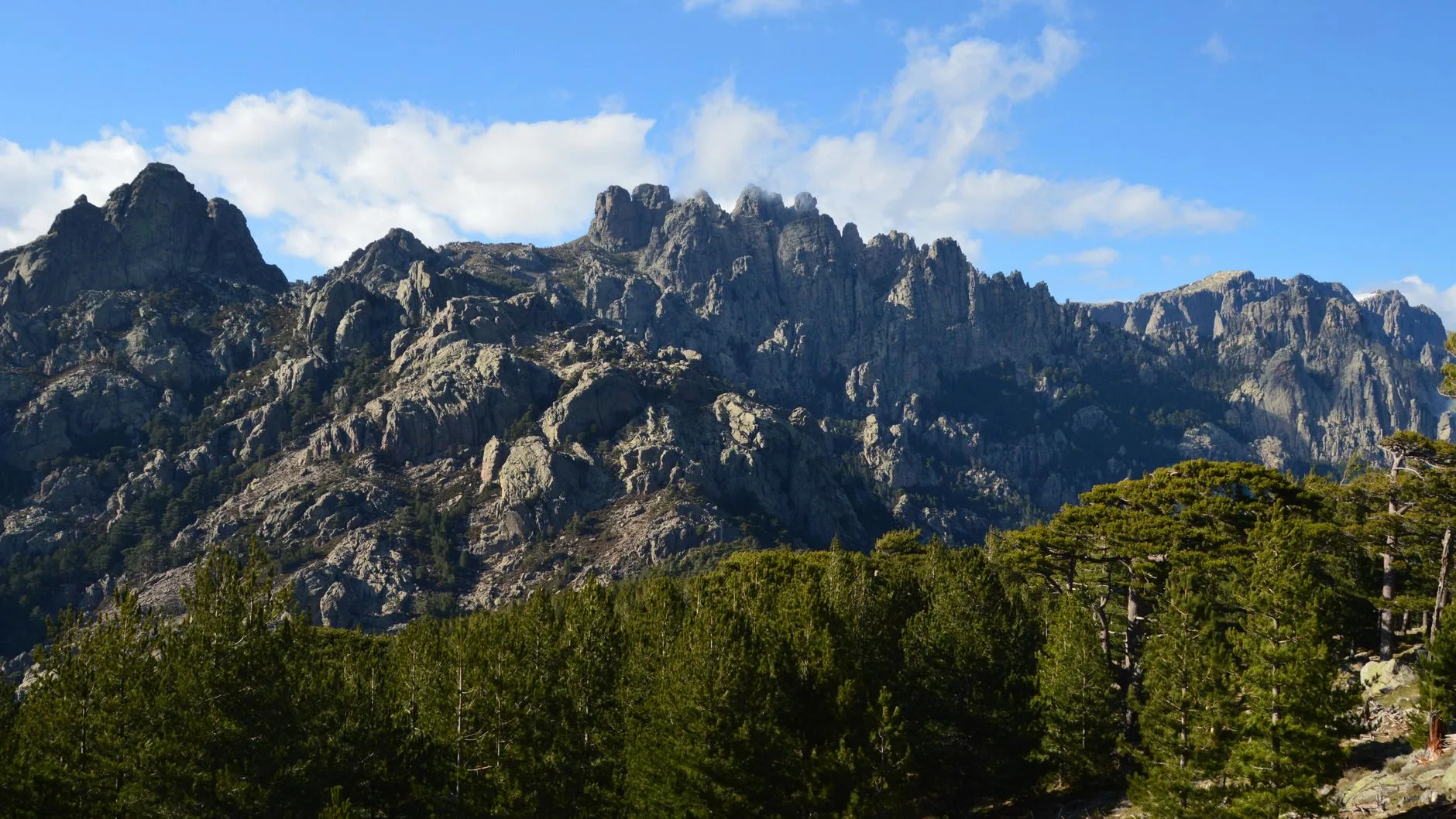 Rugged granite peaks and narrow rocky trail winding through Corsica's wild alpine landscape