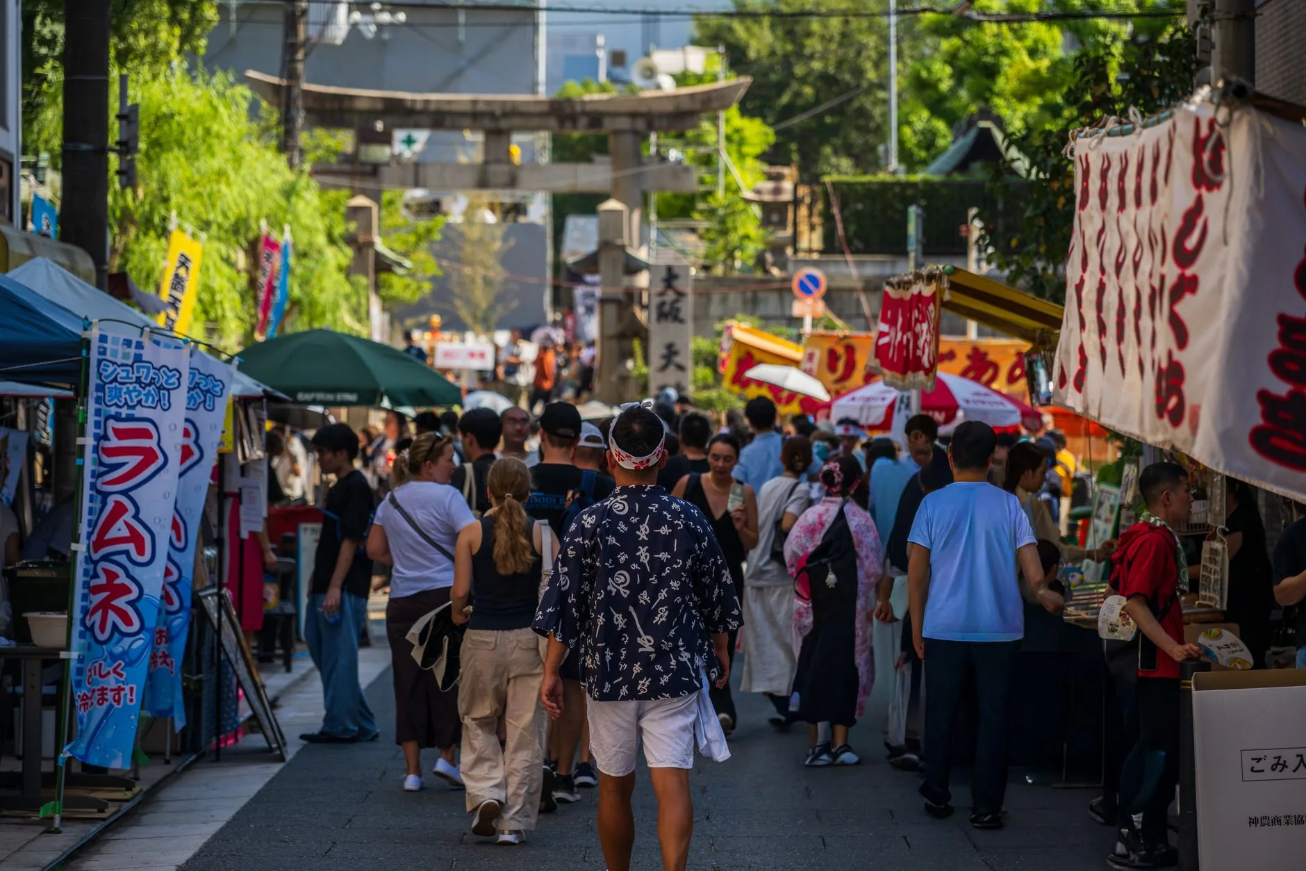 Tourists watching a lantern-lit Japanese festival parade with taiko drummers and food stalls