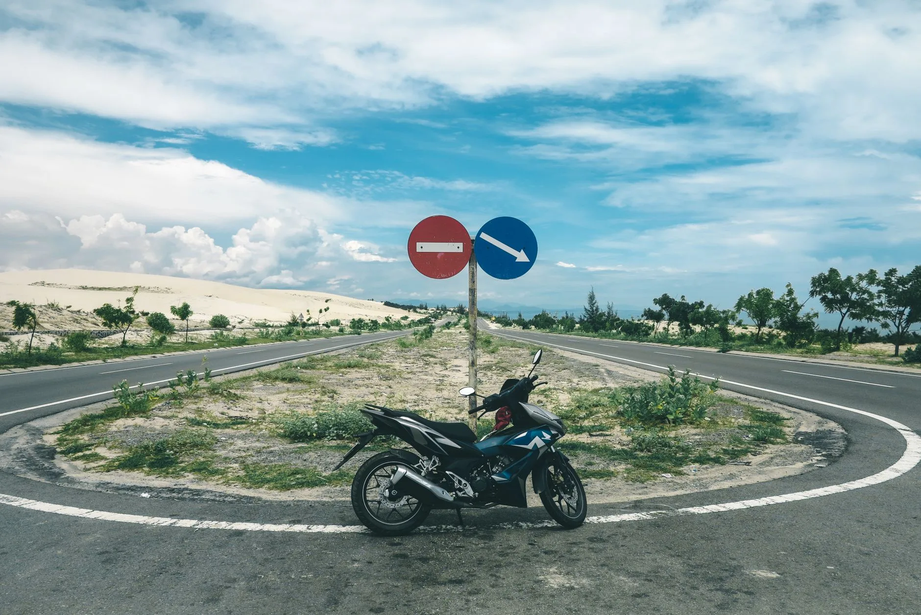 Motorcyclist riding a winding mountain road through lush Southeast Asian jungle at sunset