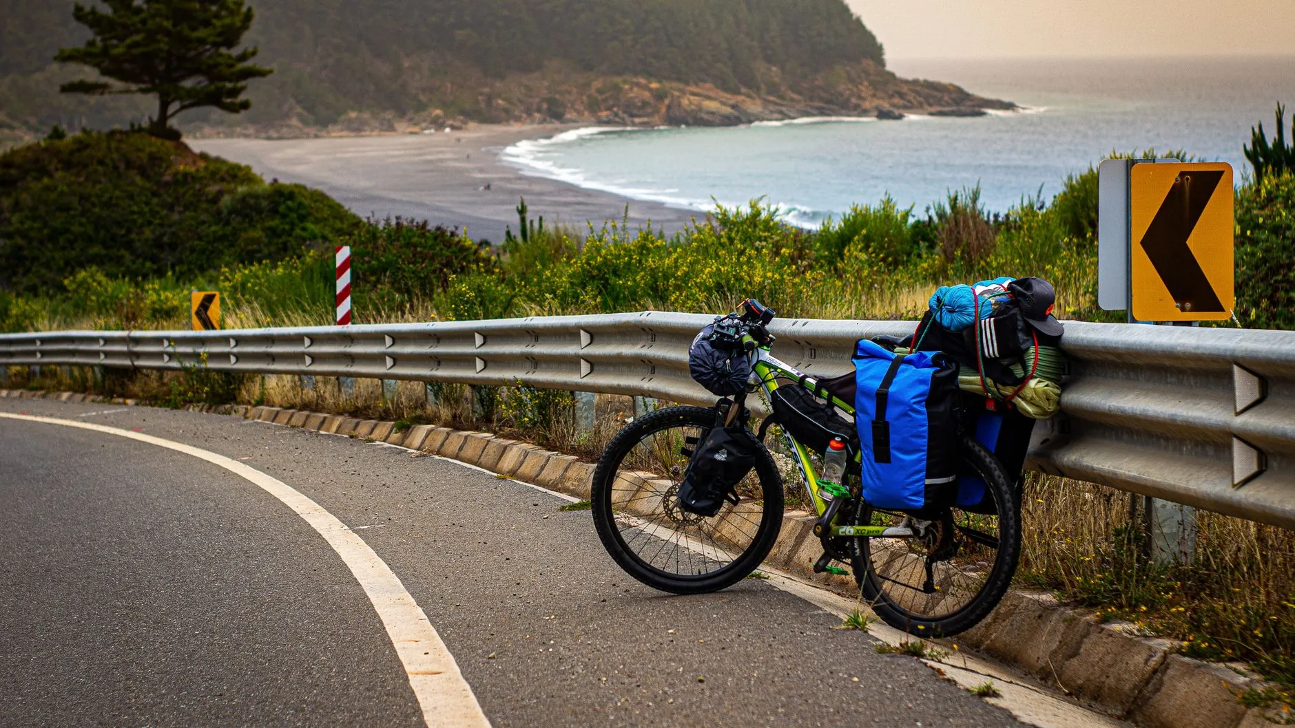 Cyclist riding a loaded touring bike along a scenic European countryside road