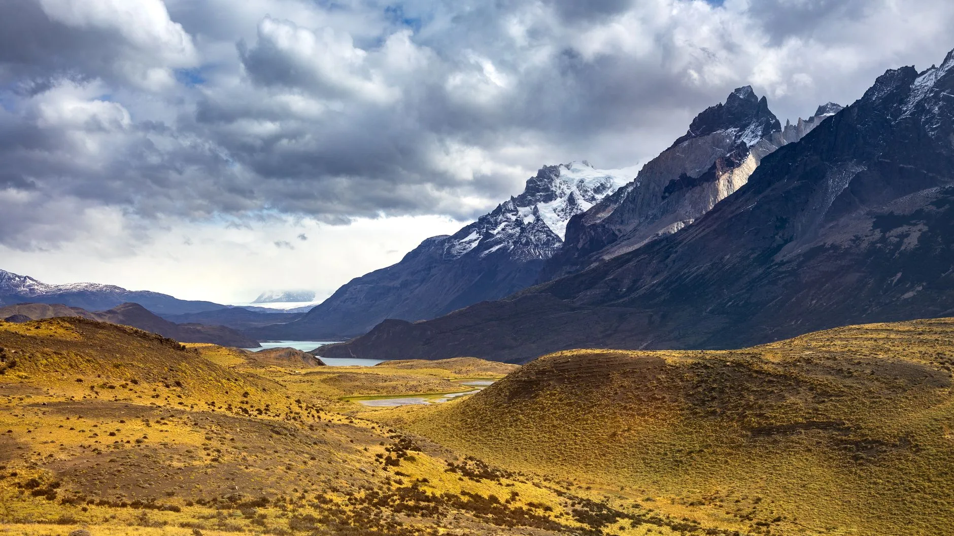 Jagged granite peaks rise above a turquoise lake along a Patagonian hiking trail
