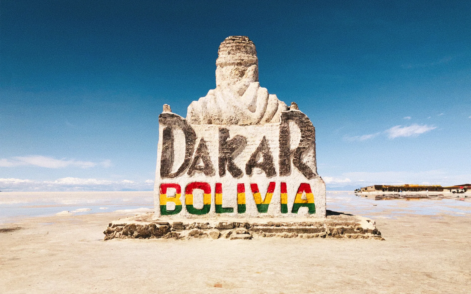 Vast white salt flats stretch to distant mountains under a brilliant blue Bolivian sky