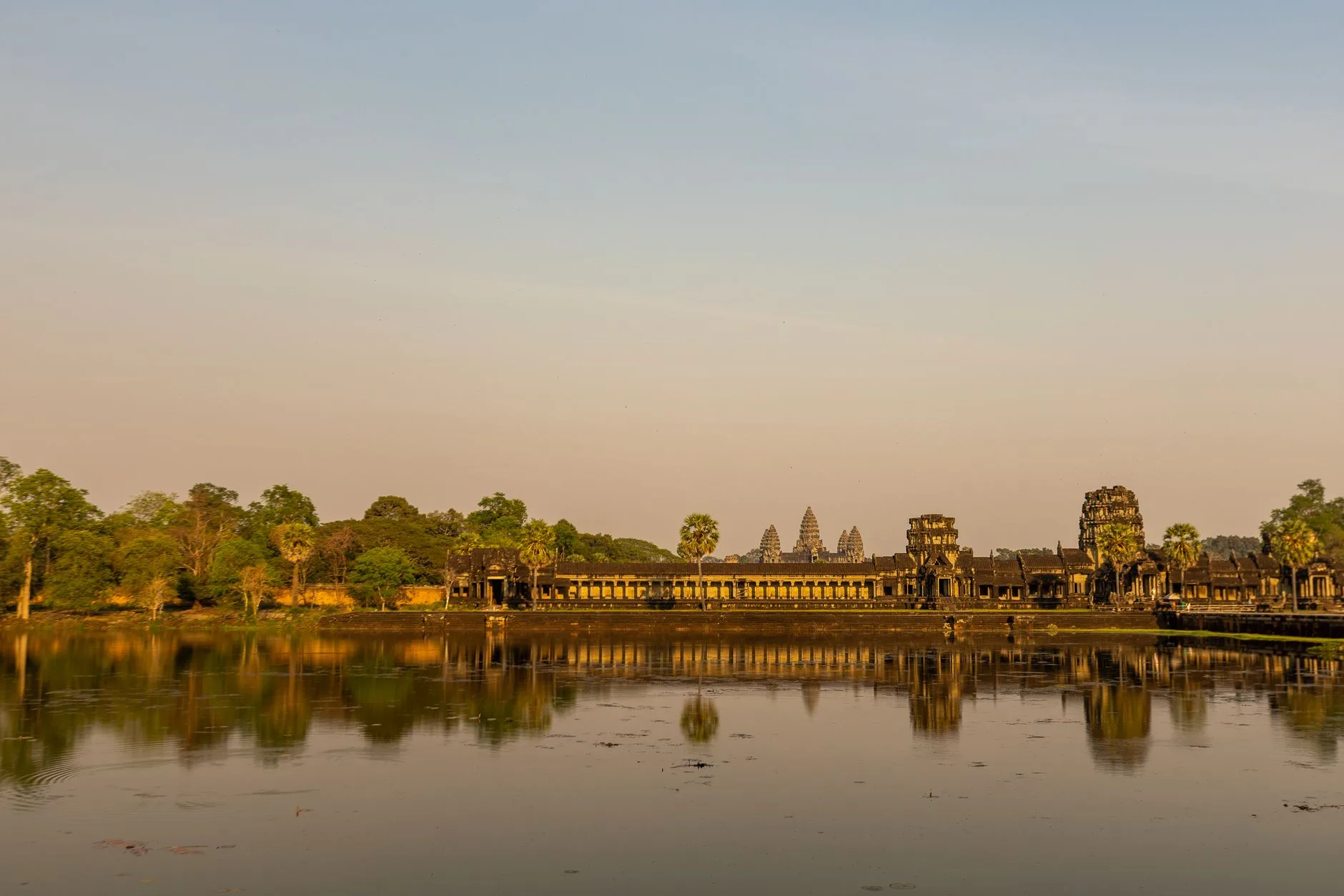 Sunrise silhouette of Angkor Wat's towers reflected in a still lotus pond