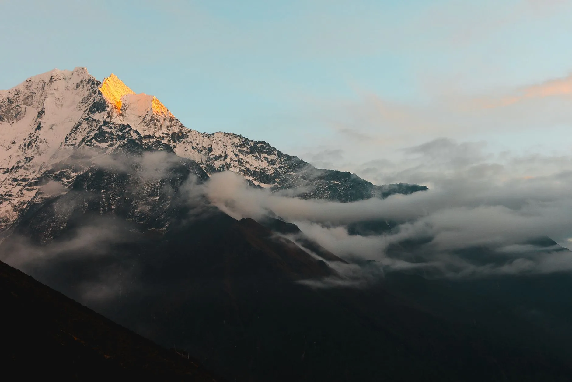 Lone trekker on a Himalayan trail, prayer flags fluttering against snow-capped peaks
