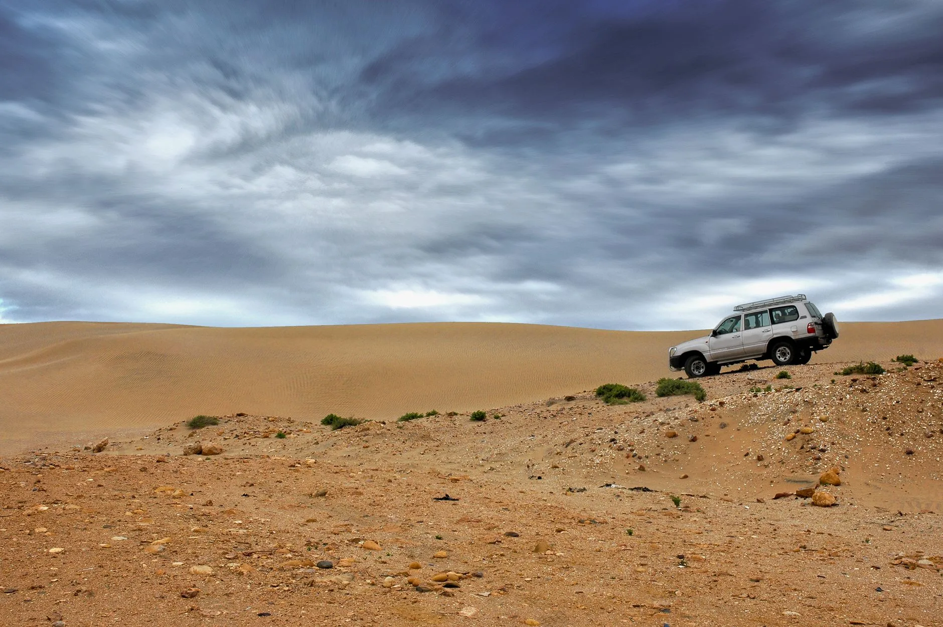 Overland 4x4 with rooftop tent parked beside a dirt track in the African bush